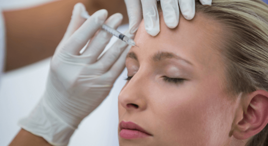 Mujer recibe tratamiento de Alluzience Botox con una aguja en el área de la frente